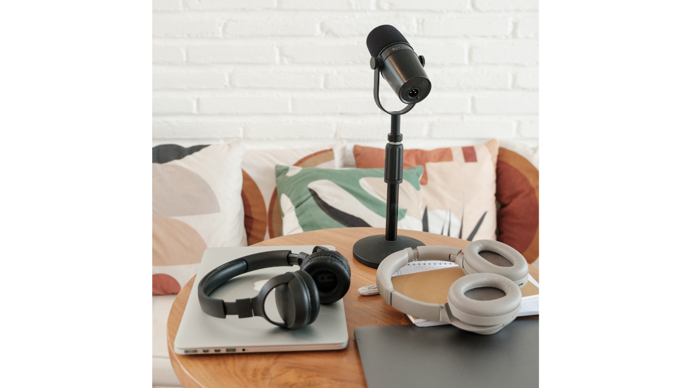 Image shows a sofa with cushions behind a table with two laptops, headphones and a microphone.